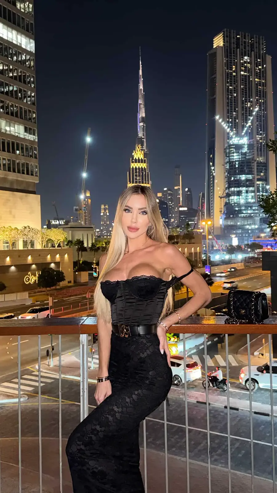Evening fashion portrait with illuminated city backdrop.